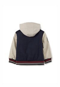 Chaqueta con capucha en azul marino y crema, con puños y cinturilla acanalados. Presenta una textura suave y un parche en la parte superior de la manga.