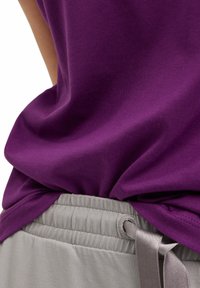Paarse katoen t-shirt, casual gedrapeerd, gecombineerd met lichtgrijze broek met elastische tailleband en satijnen trekkoord, met een gathered textuur.