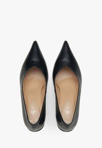 Zwarte leren pumps met spitse neuzen en uitsnijdingen aan de zijkanten, met een tan kleurige binnenzool. Ze hebben een gladde textuur en een minimalistisch ontwerp.