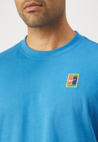 Blå bomull crewneck t-skjorte med en flerfarget Nike-logo på venstre bryst. Glatt tekstur med kortermet.
