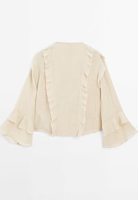 Blouse beige avec longues manches évasées et détails de volants verticaux sur le devant et les manches, étalée à plat sur fond blanc.