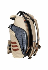 Beige rugzak met zwarte banden, ritssluiting en een patroon aan de binnenkant. Heeft een zijvak en bruine accenten. Versterkte achterkant voor ondersteuning.