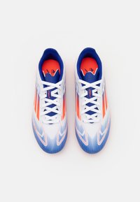 Botas de fútbol en blanco, azul y naranja. Presentan un diseño elegante con rayas diagonales, parte superior texturizada y acentos de colores contrastantes.