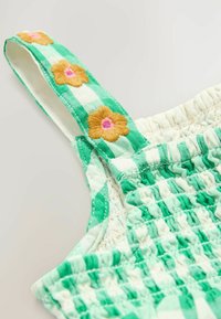 Vestido a cuadros verde y blanco con detalle de fruncido elástico, que presenta bordados florales en amarillo y rosa en los tirantes.