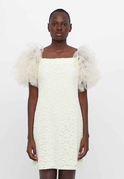 Robe blanche en dentelle avec un décolleté carré, un buste texturé et des manches bouffantes en tulle transparent. Coupe droite avec un ourlet juste au-dessus du genou.