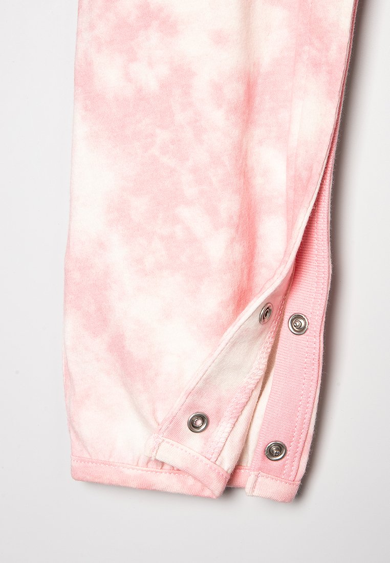 Tejido de estilo tie-dye en tonos rosas con una textura suave que presenta cierres a presión a lo largo del dobladillo. La mezcla transita de tonalidades claras a más oscuras de rosa.