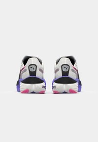 Des chaussures de sport noires, blanches et violettes avec un dessus texturé, une semelle rembourrée et des accents en caoutchouc rose sur la semelle extérieure. Présente le logo Puma.