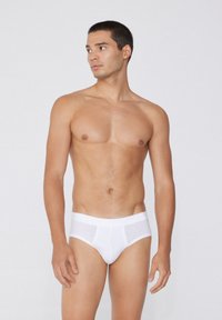 Bílé bavlněné trenýrky se měkkým elastickým pasem a průhlednými předními a bočními panely, přiléhavý střih a minimální švy.