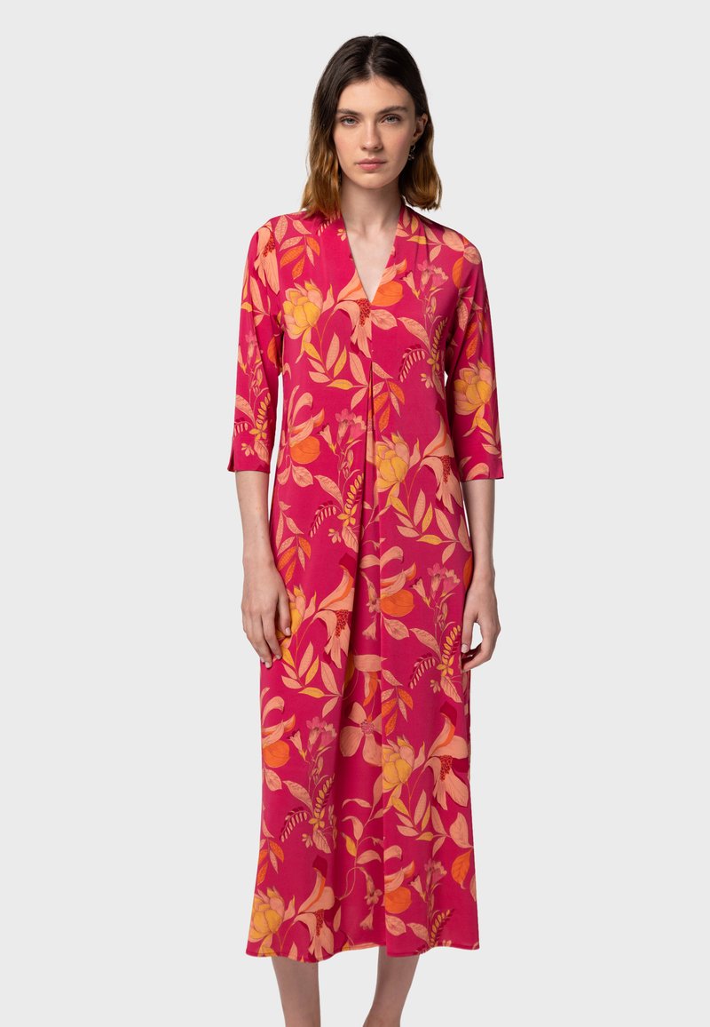 Abito in stile kimono floreale di un vivace colore rosa, con fiori arancioni e gialli, lungo fino al polpaccio e con maniche a tre quarti. Tessuto morbido.