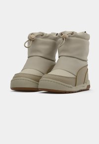 Beige waterdichte laarzen met een gestructureerde bovenkant, elastische manchet en rubberen zool. Beschikt over tonale stiksels en een laag profiel ontwerp.