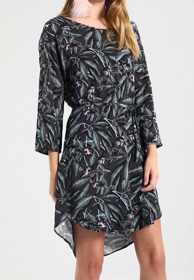 Vestido negro con un patrón de hojas botánicas en verde y rosa. Mangas largas, corte relajado y un dobladillo asimétrico. Tejido ligero.