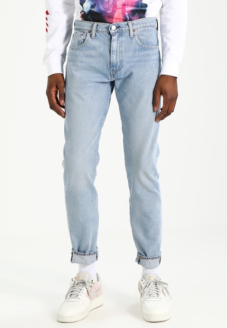 Ljusblå jeans med rak passform, hög midja, fem fickor och uppvikta nederkanter. Kombinerat med vita sneakers.