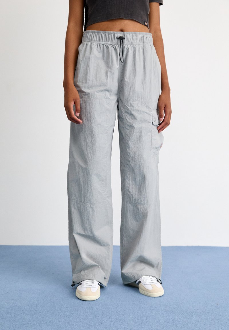 Světle šedé cargo kalhoty s elastickým pasem, bočními kapsami a texturovanou látkou. Délka pod kotníky s volným střihem.