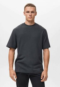 Tmavě šedé tričko s krátkým rukávem vyrobené z bavlny, s kulatým výstřihem a pohodlným střihem, s hladkou texturou a minimalistickým designem.