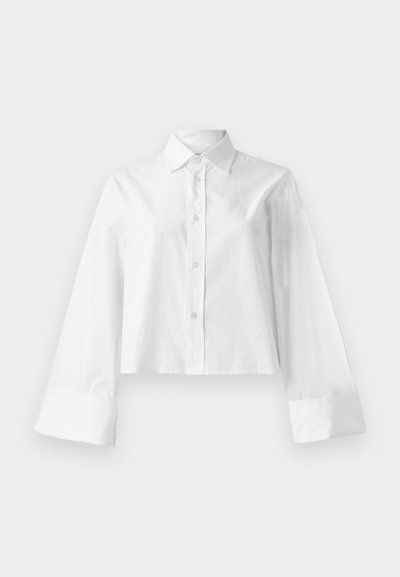 Bela skrajšana srajca z gumbastim zapiranjem spredaj, klasičnim ovratnikom in dolgimi širokimi rokavi s podrobnostmi na manšetah. Narejena iz gladkega bombažnega materiala.