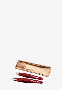 Pinces à épiler rouges avec des embouts en argent et gravées "TweezerMan," accompagnées d'une élégante étui en cuir doré. Trois pièces au total, au design compact.