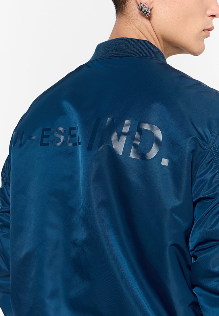 Veste de bombardier marine avec une finition brillante, un col côtelé et le texte "DI-SEL IND." en finition mate dans le dos.