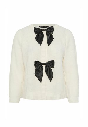 Gilet en tricot crème avec deux noeuds en satin noir à l'avant. Présente une texture côtelée et un col rond avec de longues manches légèrement bouffantes.