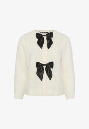 Cardigan in maglia di colore crema con due fiocchi neri in satin sul davanti. Presenta una texture a coste e un collo rotondo con maniche lunghe e leggermente puff.