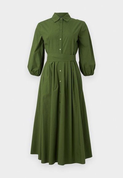 Dlhé šaty v lesnej zelenej farbe s dlhými rukávmi, priliehavým pásom, predným zapínaním na gombíky a splývavou sukňou. Obsahujú golier a naberané rukávy.
