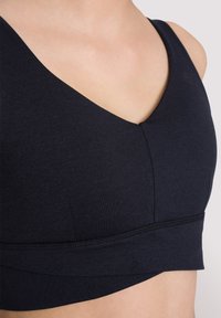 Navy sportbeha van zacht, rekbaar materiaal met een V-halsdesign, naadloze randen en een brede onderband voor ondersteuning.