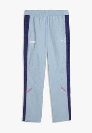 Pantalon de survêtement bleu clair avec des panneaux latéraux bleu marine, des accents violets, une ceinture élastique et les logos Puma et F1 blancs à l'avant.