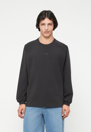 Felpa grigia scura a maniche lunghe con scollatura rotonda e maniche raglan; tessuto morbido, branding minimal sul petto, vestibilità rilassata.