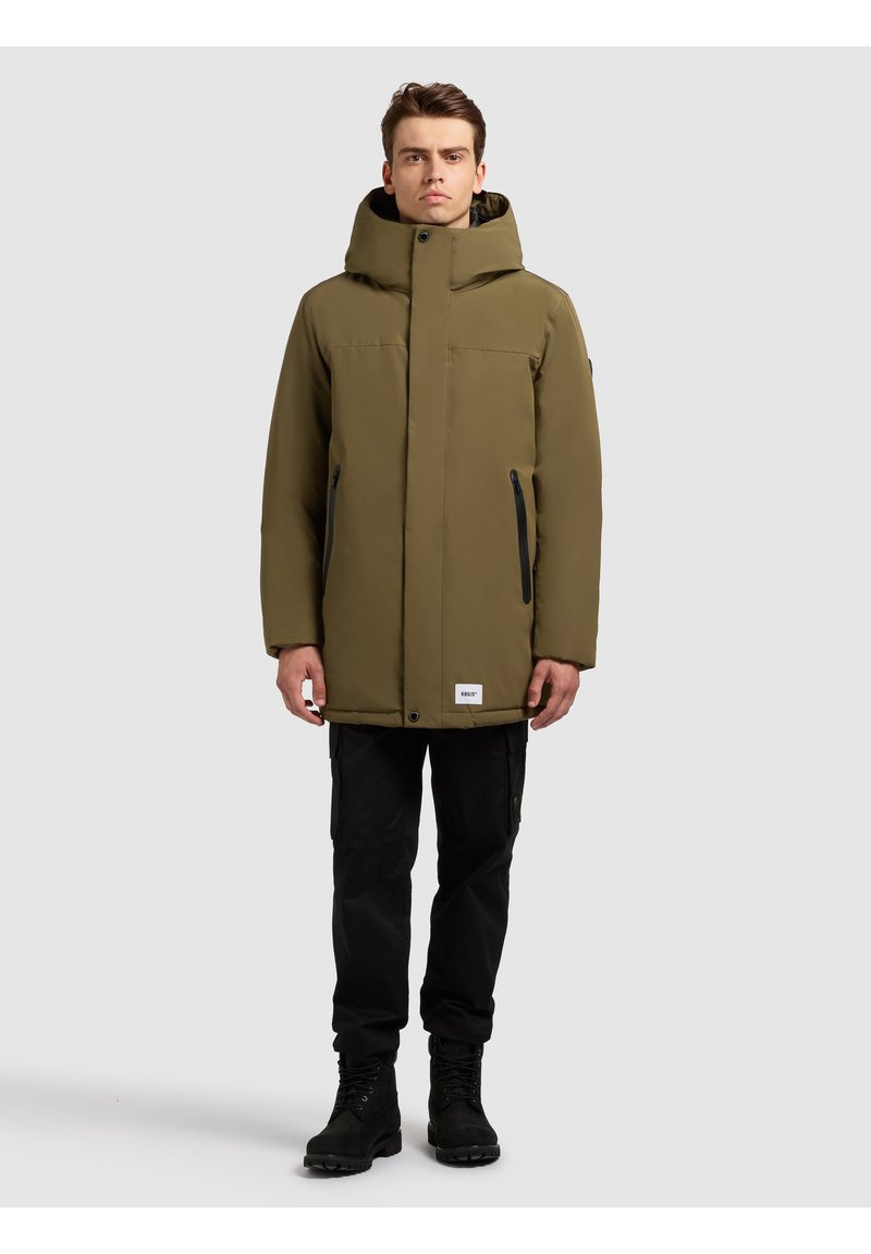 Olivengrøn isoleret jakke med høj krave og hætte, der har to lynlåslommer i siden og et logo på kanten.