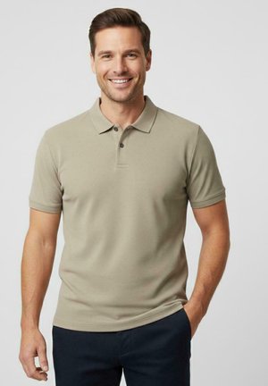 Polo shirt in lichtbeige met een geweven textuur, korte mouwen en een knoopsluiting met twee knopen. Draagt bijpassend donkerblauwe broek.