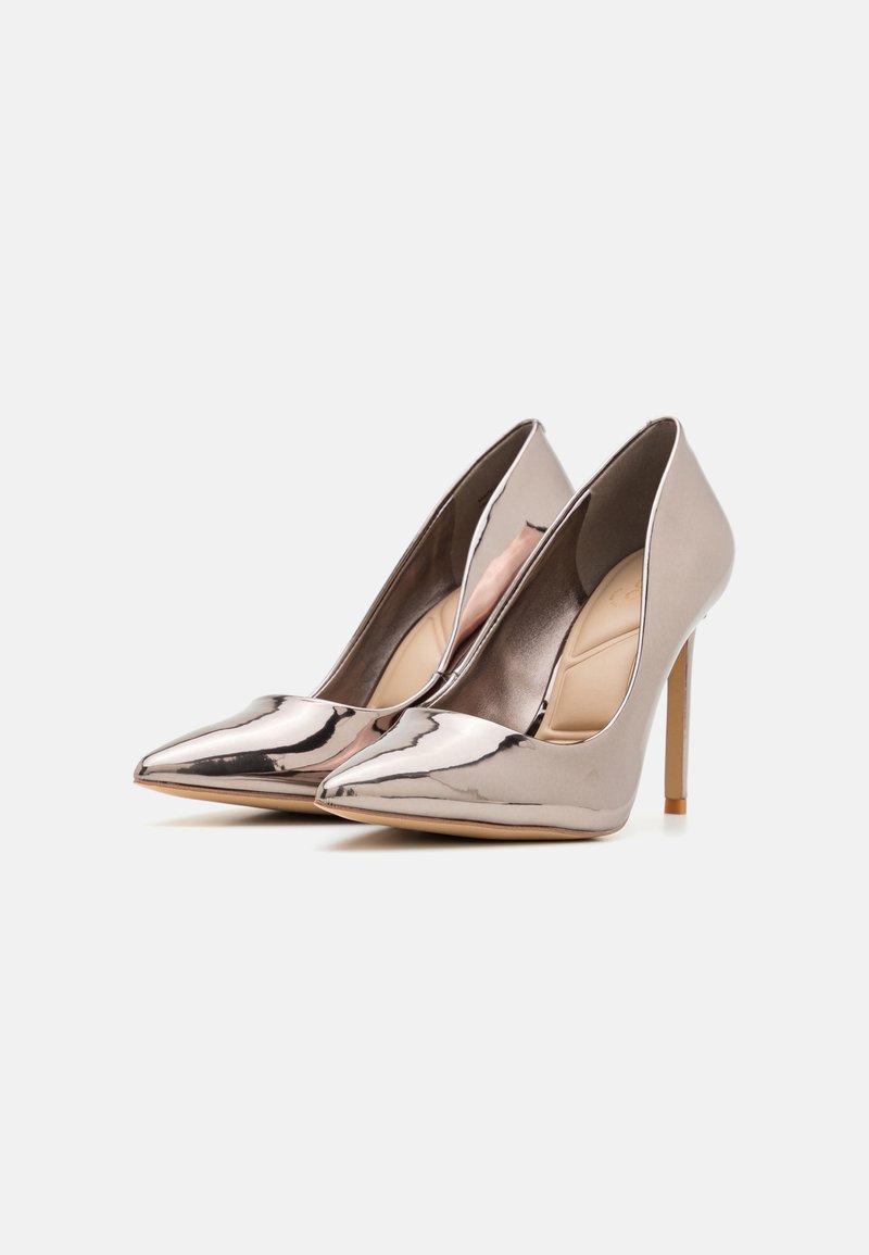 Chaussures à talons aiguilles brillantes et métalliques avec un design à bout pointu, présentant une silhouette élégante et un fin talon stiletto.