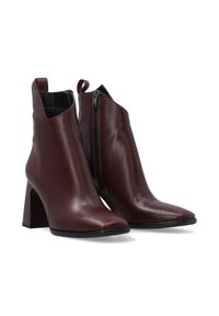 Bottines en cuir bourgogne avec un bout pointu, un talon carré et une fermeture éclair sur le côté. Texture lisse et design minimaliste.