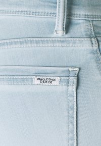 Ljust blå denimjeans med en liten bakficka som har en 'Marc O'Polo DENIM'-etikett. Tyget har en jämn textur och jämn sömnad.