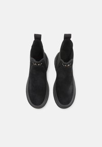 Sorte semskede ankelboots med elastiske sidepaneler og lækker tab, med en tekstureret sål og diskret brandingdetalje i guld.