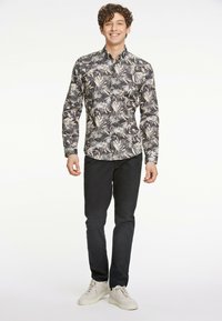 Langsleeve button-up shirt met een zwart en roomkleurig bladerenpatroon, gecombineerd met zwarte broek en beige sneakers. Soepele stof, passend ontwerp.