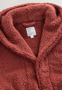 Rust-colored, plush fleece bathrobe with a textured surface, large hood, and tag displaying "NEXT time to dream." Soft, cozy material.