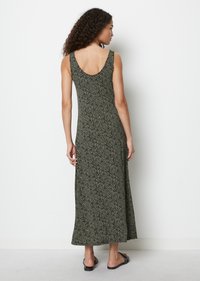 Schwarzes und cremefarbenes gemustertes Maxikleid mit rundem Rückenausschnitt, aus weichem Stoff gefertigt, mit tailliertem Oberteil und weit schwingendem Rock. Getragen mit schwarzen Sandalen.