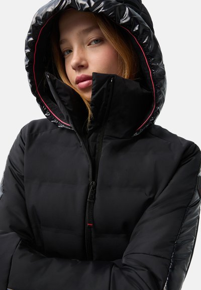 Black puffer jacket with a glossy hood, front zipper, and contrasting red lining; features quilted texture and an adjustable fit.