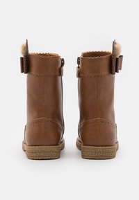 Brązowe botki za kostkę z ekologicznej skóry z falistymi krawędziami, dekoracyjnymi zapięciami na klamry i teksturowaną gumową podeszwą.