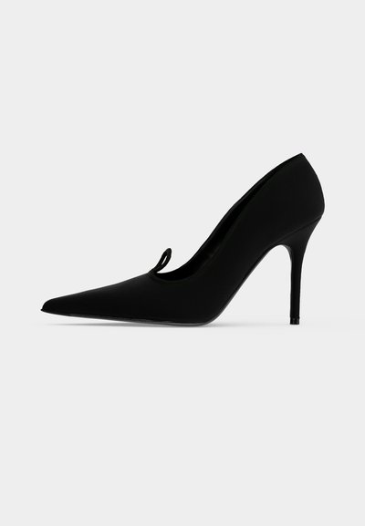 Chaussure à talon haut noire à bout pointu avec talon stiletto et petit détail en boucle sur la partie supérieure, vue de profil gauche.