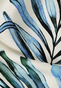 Tissu avec des motifs de feuilles tropicales bleu et vert sur un fond crème. Le design présente des coups de pinceau audacieux et un tissu texturé.