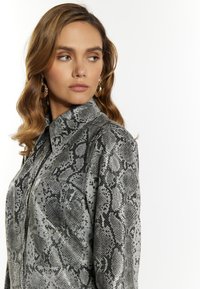 Zilveren slangenprintblouse met knoopsluiting, kraaghals en een gladde stoftextuur. Heeft een overshirtontwerp met kenmerkende patronen.