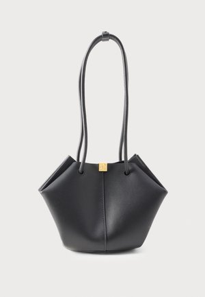 Sac à main en cuir noir avec une forme géométrique originale, longues doubles anses, et un petit emblème carré doré au centre supérieur.
