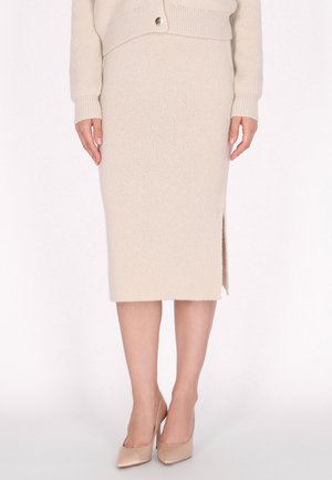 Beige gestrickter Bleistiftrock mit einem seitlichen Schlitz, kombiniert mit nudefarbenen High Heels. Der Stoff hat eine strukturierte Oberfläche und gerippte Details am Bund.