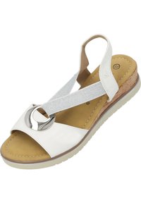 Weiße Sandale mit Korkplattform, silbernem elastischen Riemen und kreisförmigem Metallic-Detail. Weicher Fußbett mit braunem Innenleben, strukturierte Sohle.