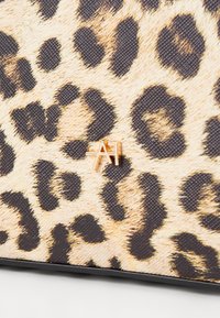 Tissu à motif léopard avec une texture tactile et une quincaillerie dorée affichant en évidence les initiales "A" et "F".