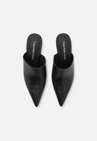 Mules en cuir noir avec un bout pointu et un dos ouvert. Dotés d'une texture lisse et d'un branding subtil sur la semelle intérieure.