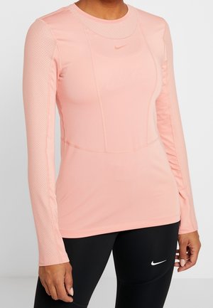 Long-sleeve athletic shirt in soft pink fabric with mesh accents on sleeves, featuring a round neckline and subtle brand logo.