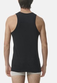 Černý bavlněný top na ramínka s kulatým výstřihem a širokými ramínky. Hladká textura, přiléhavý střih a delší zadní lem.