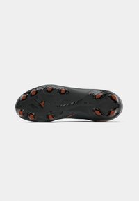 Black football boot sole with a textured surface, multiple studs, and orange accents. Design optimized for traction and performance.