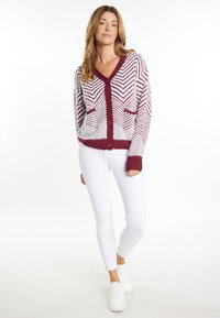 Cardigan lavorato a maglia con un motivo a zigzag in marrone e bianco, con scollo a V, chiusura con bottoni e due tasche frontali; polsini e orlo a coste.